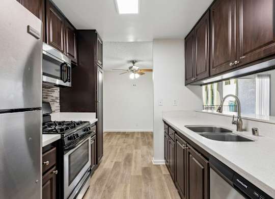 A kitchen with dark wood cabinets and stainless steel appliances.