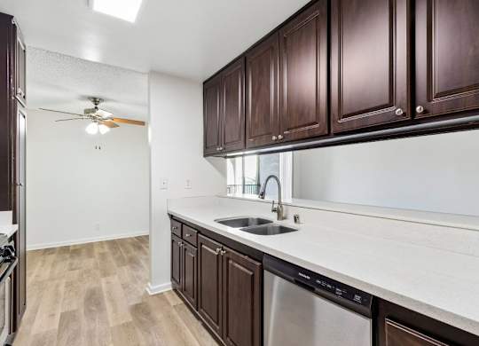 A kitchen with brown cabinets and a stainless steel dishwasher.