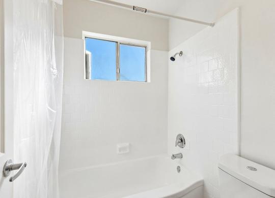 A white bathroom with a tub, toilet, and sink.