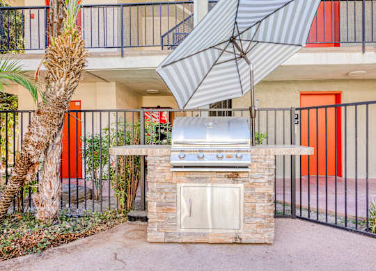 A patio with a grill and a tree.
