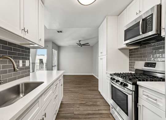 A kitchen with white cabinets and a stove top oven.