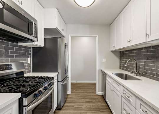 A kitchen with white cabinets and a black refrigerator.