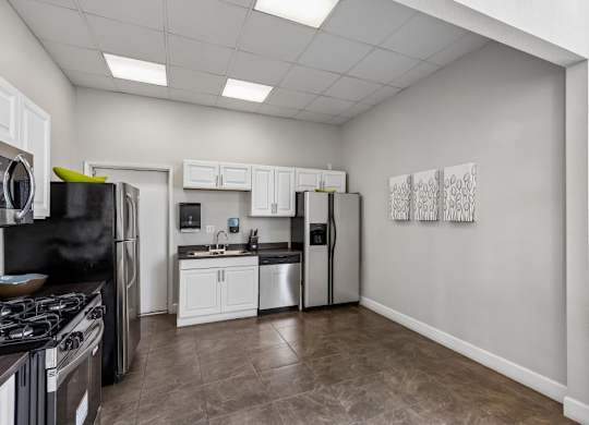 A kitchen with black appliances and white cabinets.