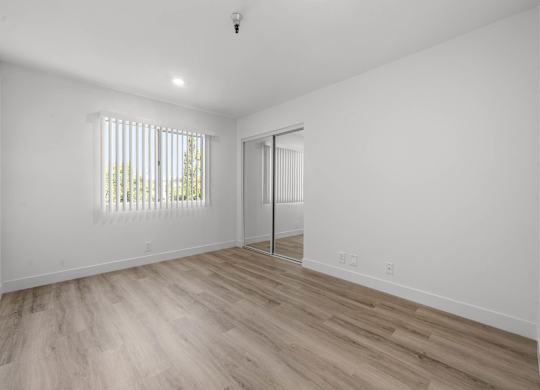 A room with a sliding door and a window with blinds.