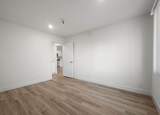 A room with wooden flooring and white walls.
