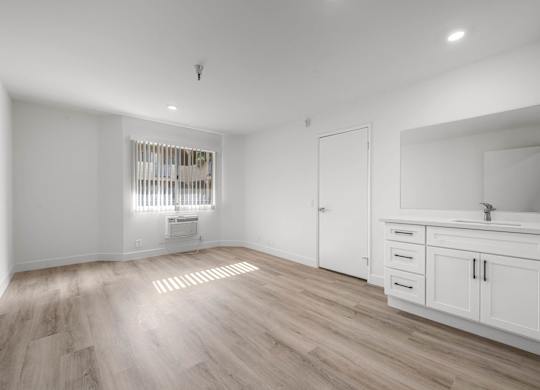 A white bathroom with a sink and a window.