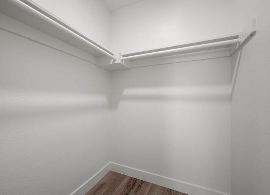 A white closet with a shelf and a wooden floor.