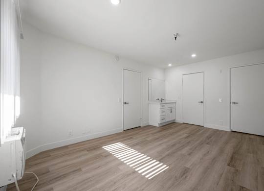 A room with wooden floors and white walls, with a radiator on the left side.