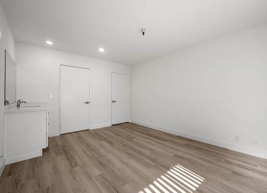 A room with a sink and wooden floors.