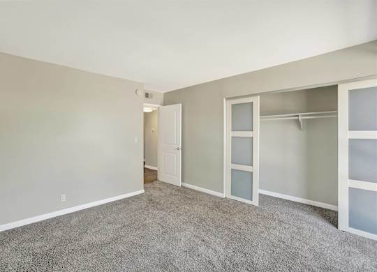 Bedroom with walk-in closet and carpeted flooring at Parc @ 5 Apartments, Downey
