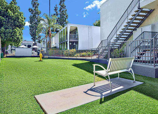 Outdoor courtyard with bench and artificial turf lawn at Parc @ 5 Apartments, Downey, CA