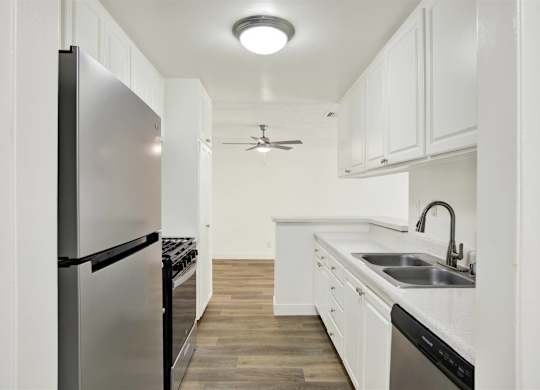 Galley kitchen with stainless steel appliances and white cabinetry at Parc @ 5 Apartments, Downey, California