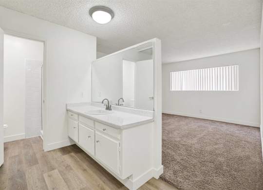 Dual vanity bathroom with carpeted bedroom view at Parc @ 5 Apartments, Downey, California