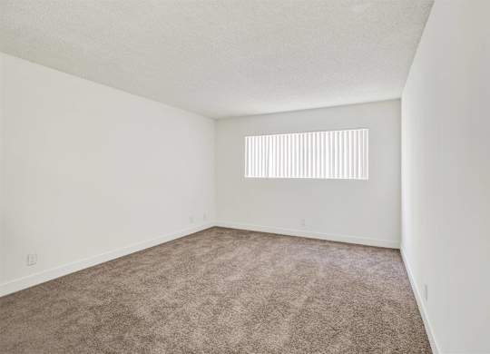 Empty carpeted bedroom with horizontal blinds at Parc @ 5 Apartments, Downey