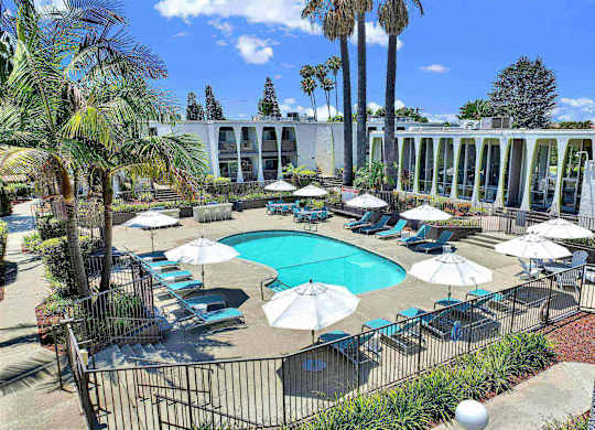 Kidney shaped pool with lounge seating and white umbrellas at Parc @ 5 Apartments, California