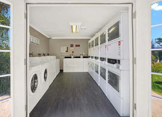 a laundry room with washers and dryers and a window at Monterra Ridge Apartments, California,91351