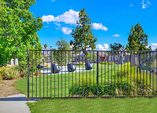 a playground in a park behind a metal fence at Monterra Ridge Apartments, Canyon Country ,91351