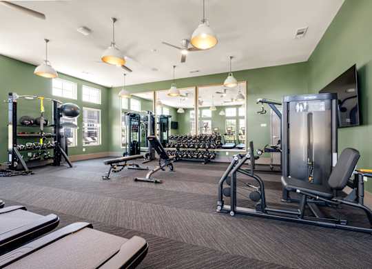 A gym with a variety of equipment including treadmills, weights, and exercise machines.