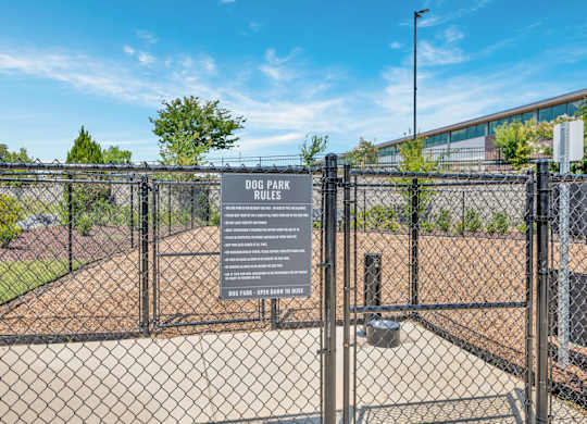 A sign in front of a fence that says Dog Park Rules.