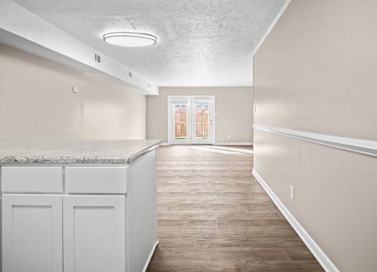 A kitchen with white cabinets and a marble countertop.