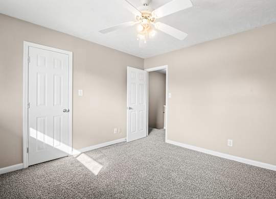 A room with a ceiling fan and two doors.