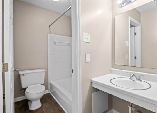 A white toilet is in a small bathroom with a white sink.