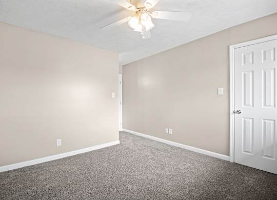 A room with a ceiling fan and a door.