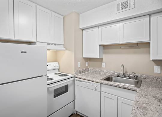 A white kitchen with a refrigerator, stove, and sink.