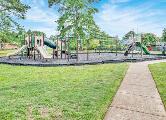 A playground with a green slide and a brown walkway.