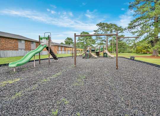 A playground with a green slide and a wooden swing set.