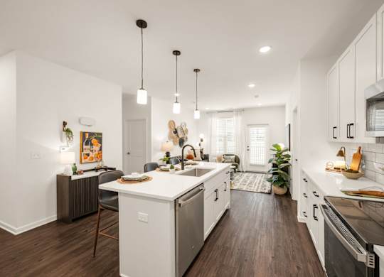 A modern kitchen with white cabinets and a wooden floor.