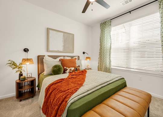 A bedroom with a bed, a bench, and a ceiling fan.