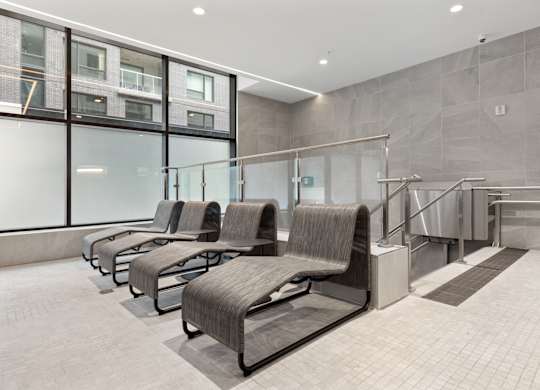 A row of grey chairs by an indoor pool at Skye rentals in Ottawa