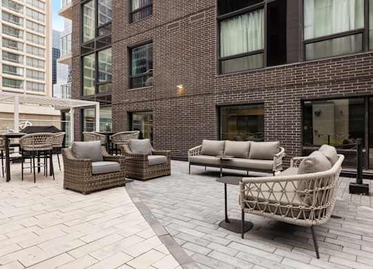 A patio with a wicker chair and table.