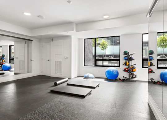 A spacious room with exercise equipment and mirrors on the wall.