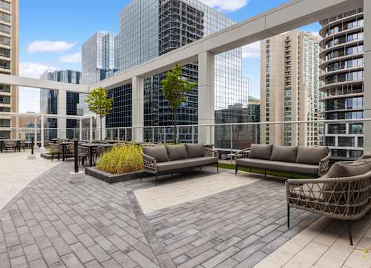 A patio with a couch and chairs with buildings in the background.