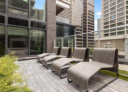 A row of grey couches are lined up on a patio.