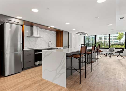 A modern kitchen with a refrigerator, sink, and bar area.