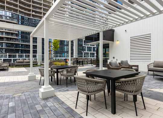 A patio with a table and chairs under a white pergola.