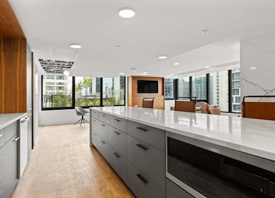 A modern kitchen with a long counter and a view of the city.