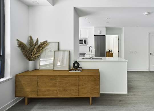 a kitchen and living room with white walls and a wooden dresser