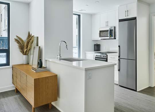 a kitchen with a white counter top and a stainless steel refrigerator