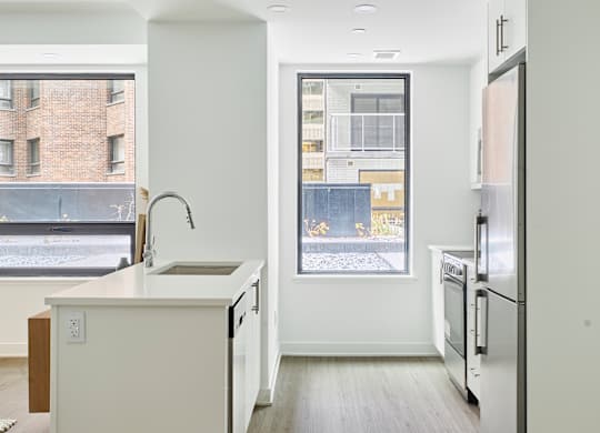 an empty kitchen with a large window and a sink and a refrigerator
