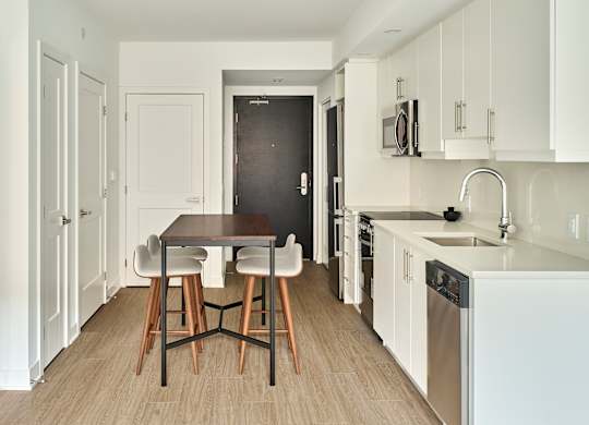 a kitchen with white cabinets and a wooden table and chairs