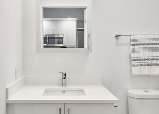 a white bathroom with a sink toilet and mirror