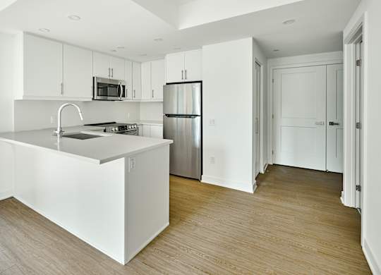 an empty kitchen with white cabinets and a stainless steel refrigerator