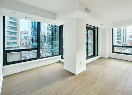 an empty living room with large windows and wood floors