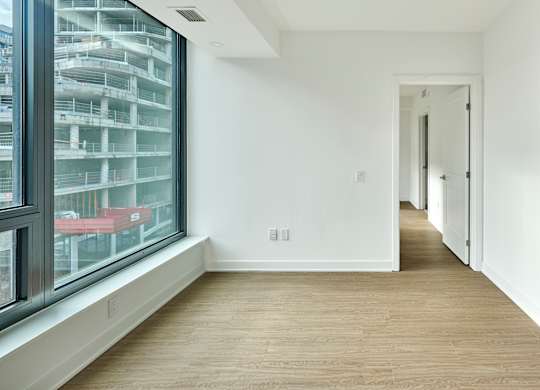 a hallway with white walls and wood floors and a large window