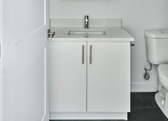 a white bathroom with a sink and mirror and a toilet