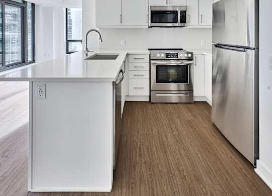 an empty kitchen with white cabinets and stainless steel appliances